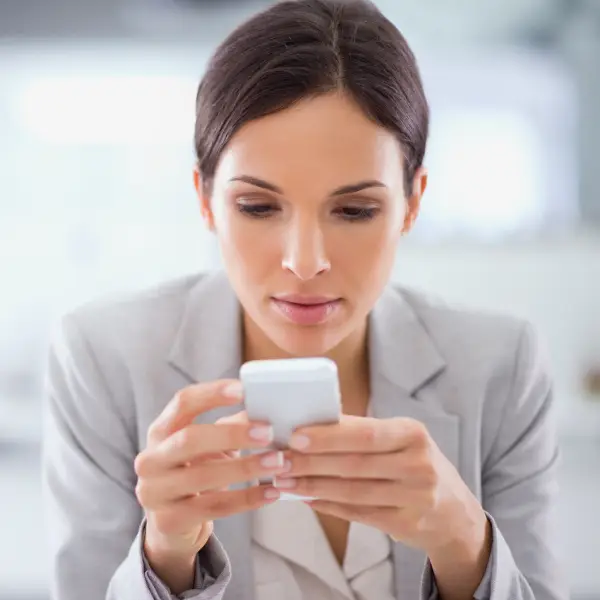 Services voyance par téléphone Jeune femme cheveux brun tenant son téléphone mobile compose un numéro de téléphon pour une voyance par téléphone au cabinet kinen voyant et médium
