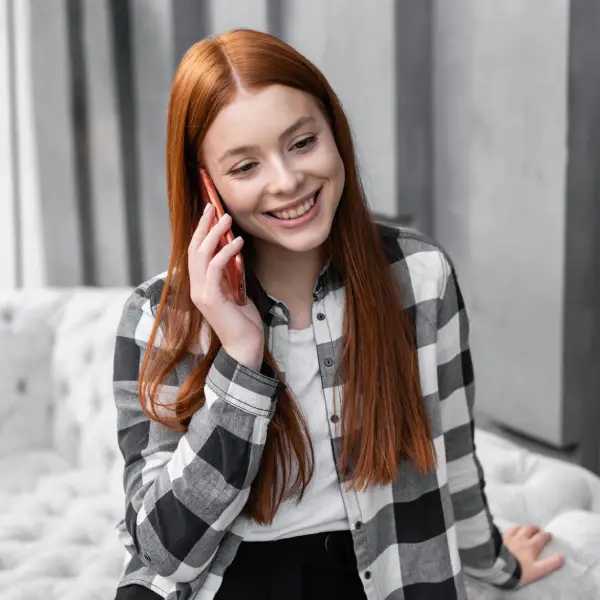 Consultation de voyance audiotel Jeune femme cheveux long couleur roux souriante parle au téléphone pendant une consultation de voyance audiotel